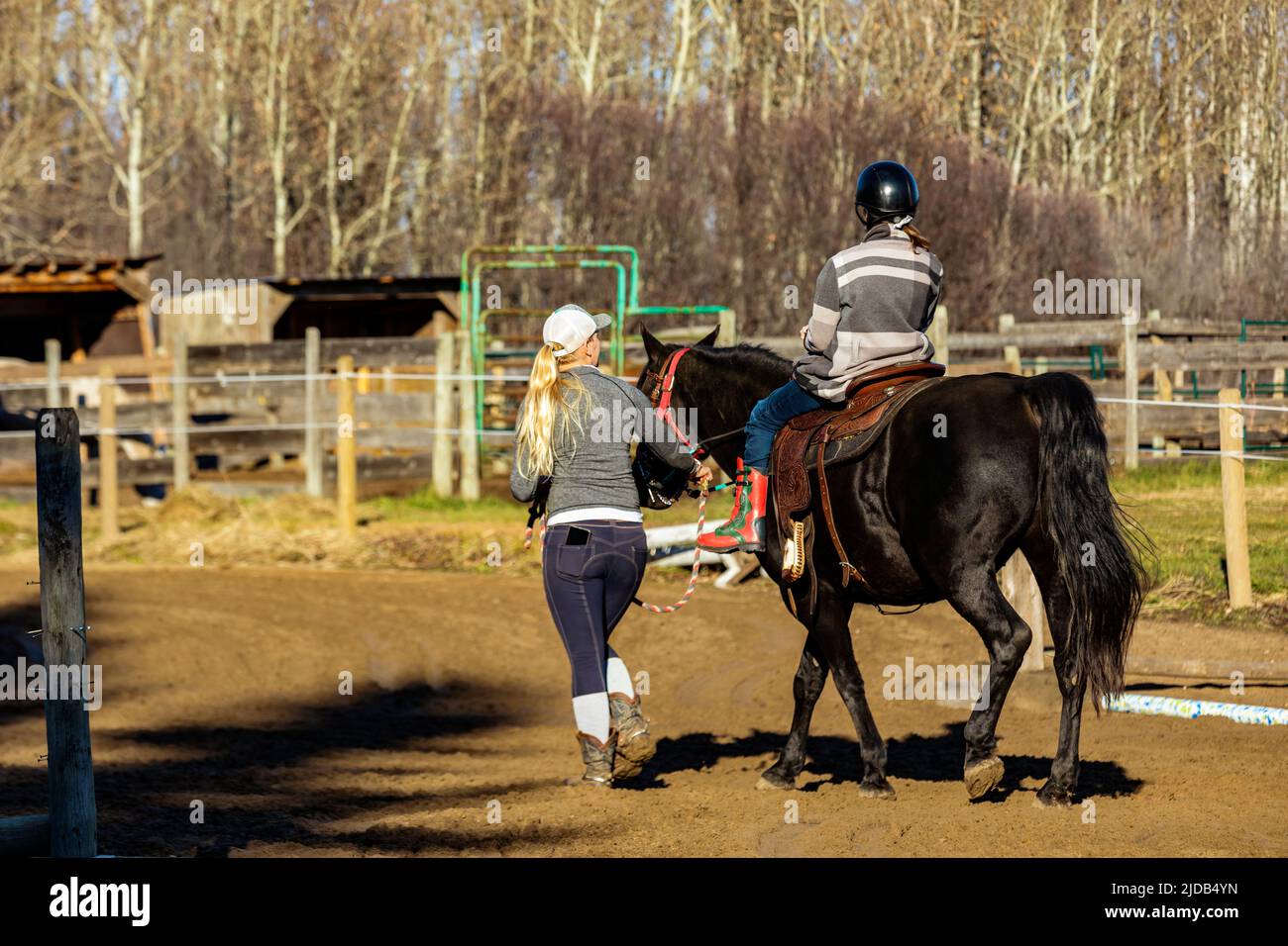 A trainer working with a young girl with Cerebral Palsy during a Hippotherapy session; Westlock, Alberta, Canada Stock Photo