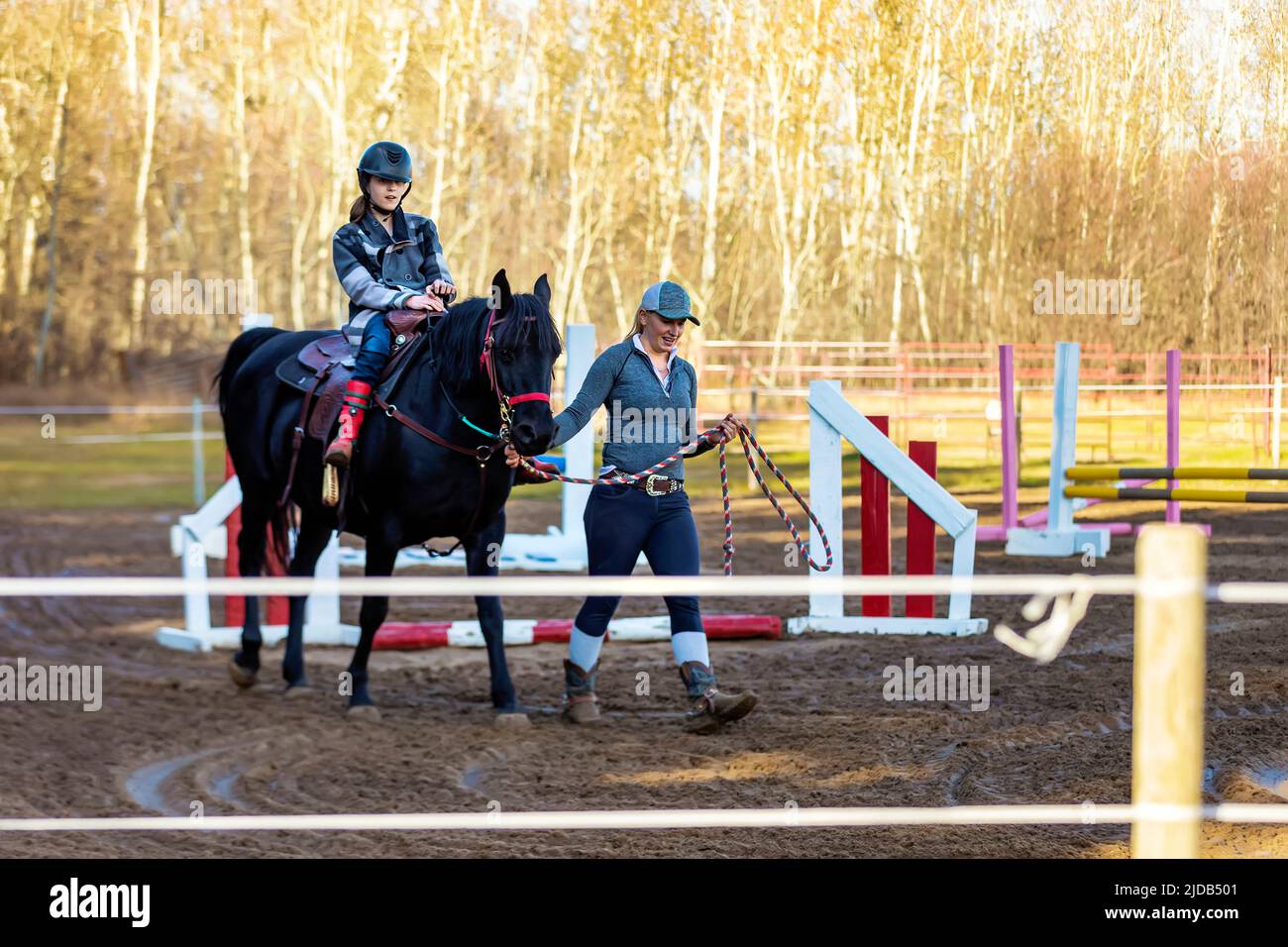 A trainer working with a young girl with Cerebral Palsy during a Hippotherapy session; Westlock, Alberta, Canada Stock Photo