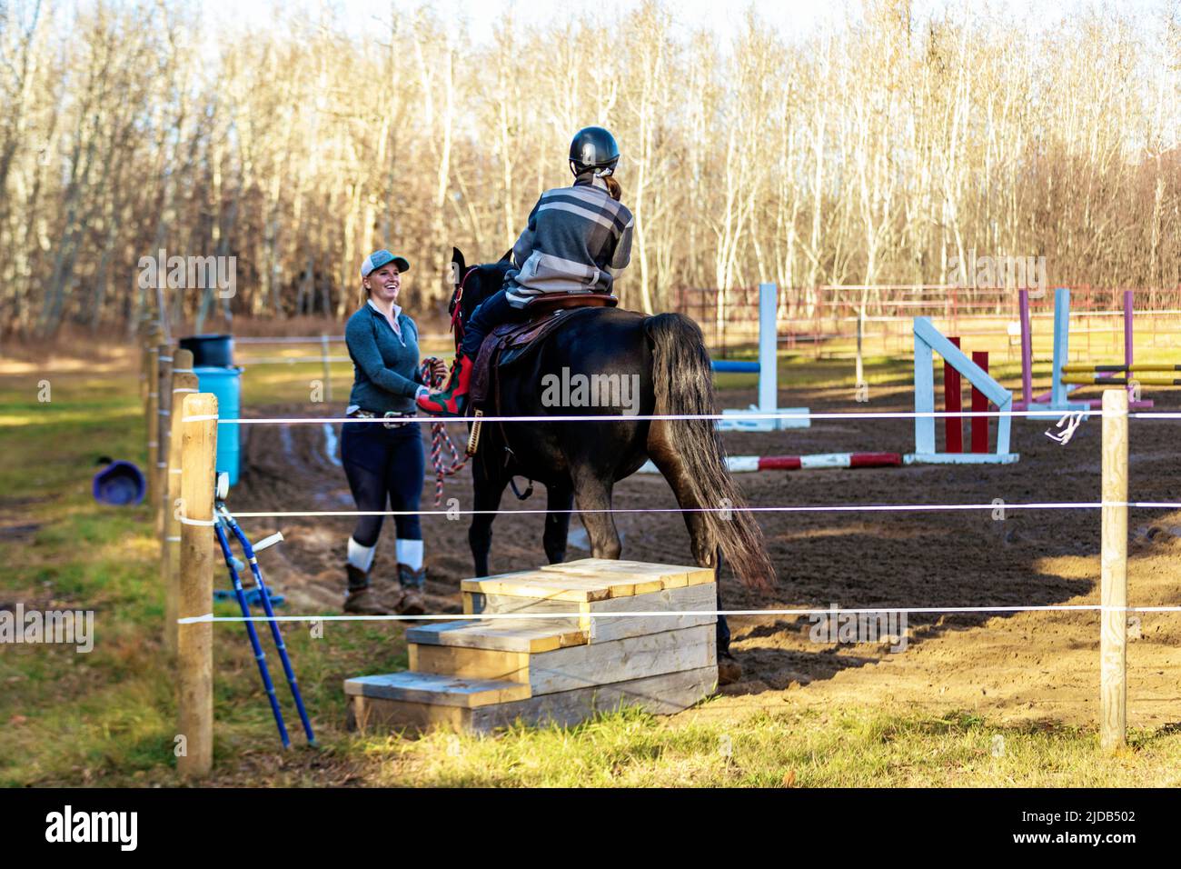 A trainer working with a young girl with Cerebral Palsy during a Hippotherapy session; Westlock, Alberta, Canada Stock Photo