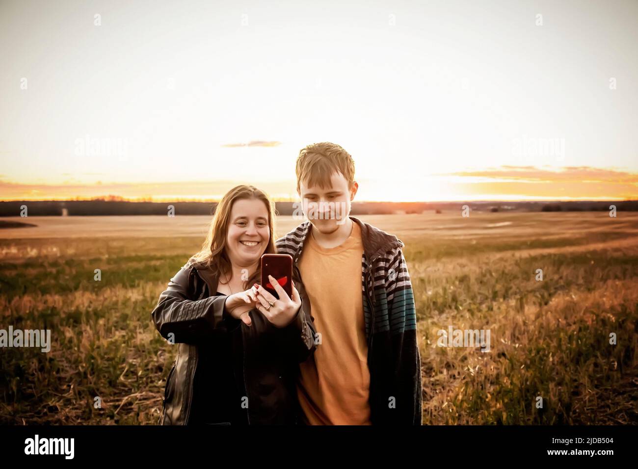 A mother with epilepsy taking a self-portrait with her son who has Aspberger Syndrome in a field on a farm after harvest; Westlock, Alberta, Canada Stock Photo