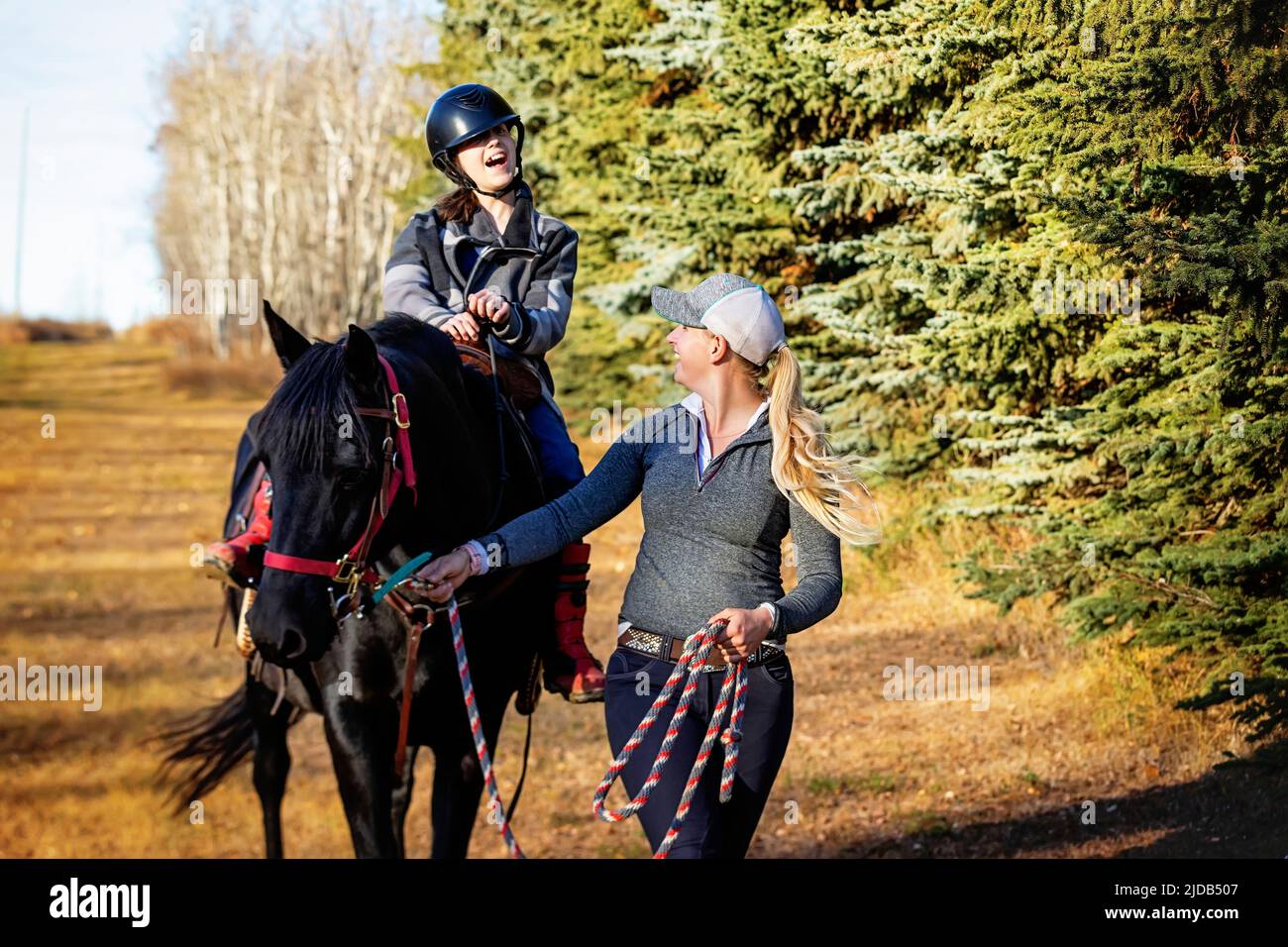 A trainer working with a young girl with Cerebral Palsy during a Hippotherapy session; Westlock, Alberta, Canada Stock Photo