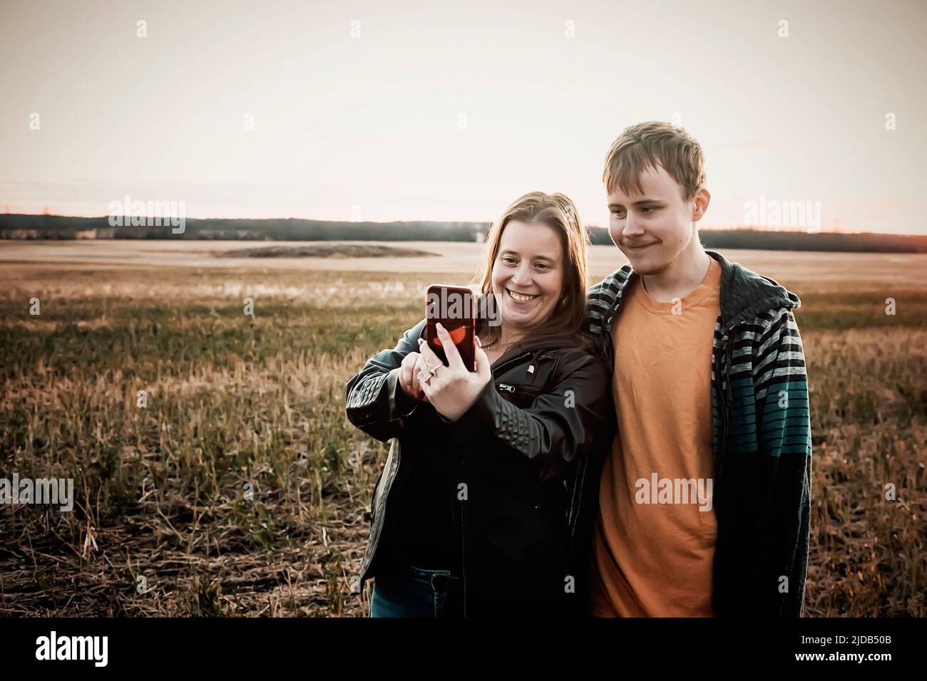 A mother with epilepsy taking a self-portrait with her son who has Aspberger Syndrome in a field on a farm after harvest; Westlock, Alberta, Canada Stock Photo