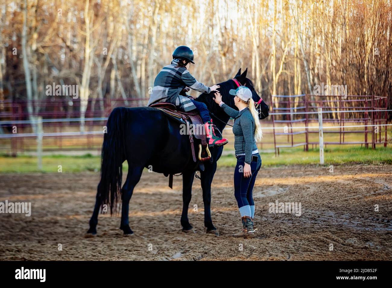 A trainer working with a young girl with Cerebral Palsy during a Hippotherapy session; Westlock, Alberta, Canada Stock Photo