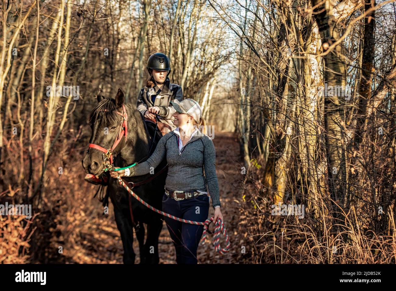 A young girl with Cerebral Palsy and her trainer working with a horse on a trail ride during a Hippotherapy session; Westlock, Alberta, Canada Stock Photo