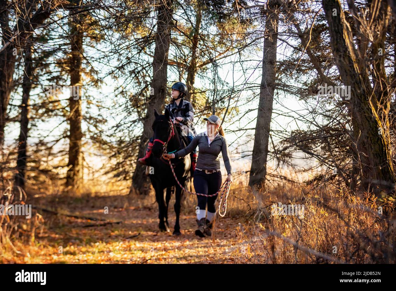 A young girl with Cerebral Palsy and her trainer working with a horse on a trail ride, during a Hippotherapy session: Westlock, Alberta, Canada Stock Photo