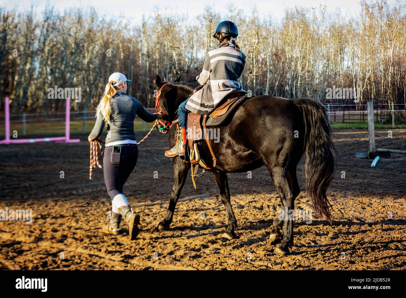 A trainer working with a young girl with Cerebral Palsy during a Hippotherapy session; Westlock, Alberta, Canada Stock Photo