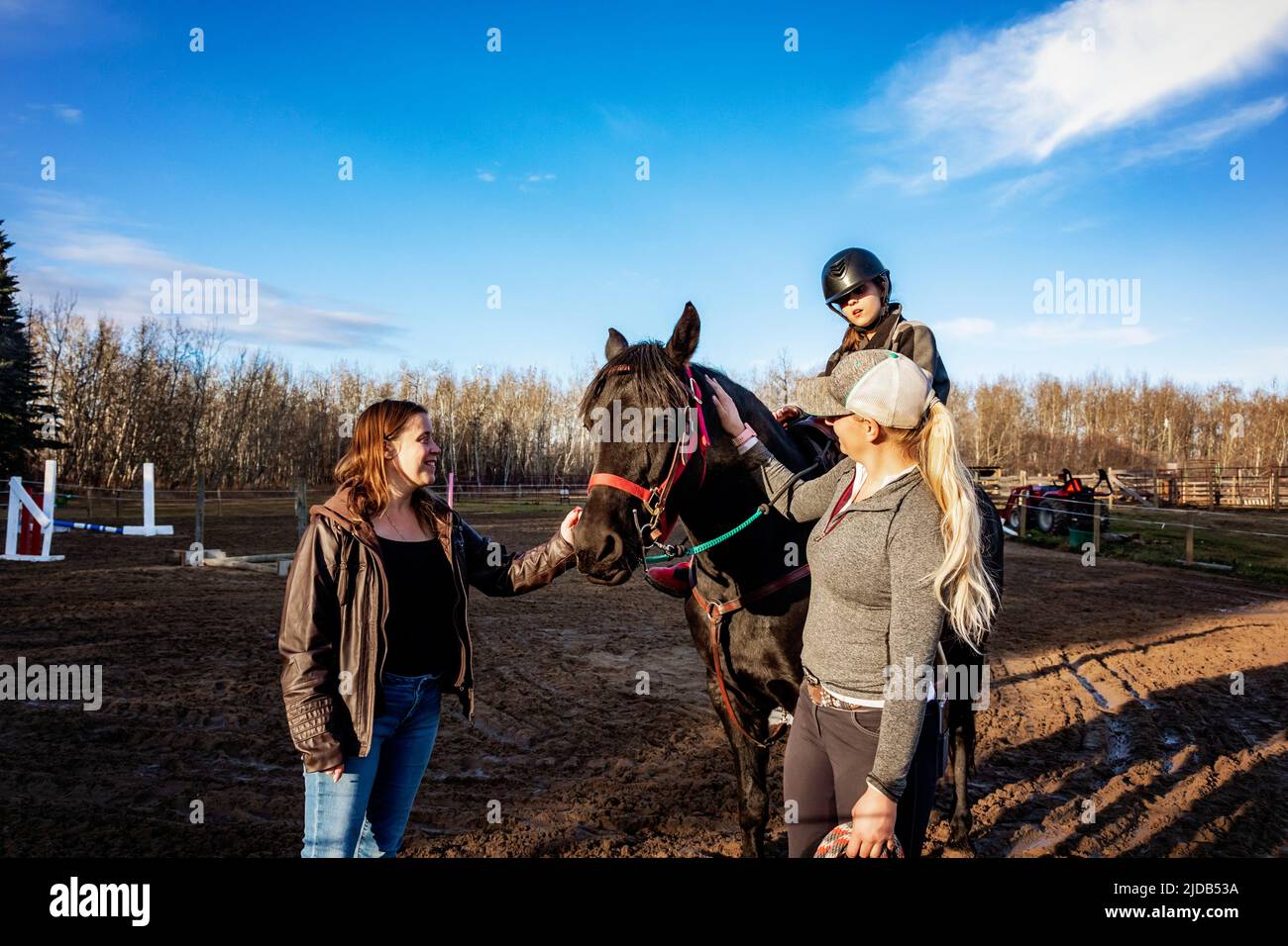 A young girl with Cerebral Palsy, her Mom and her trainer working with a horse during a Hippotherapy session; Westlock, Alberta, Canada Stock Photo