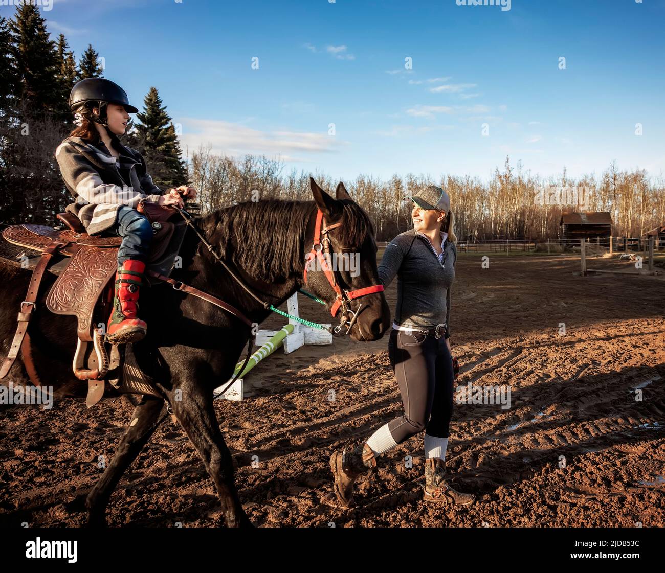 A trainer working with a young girl with Cerebral Palsy during a Hippotherapy session; Westlock, Alberta, Canada Stock Photo