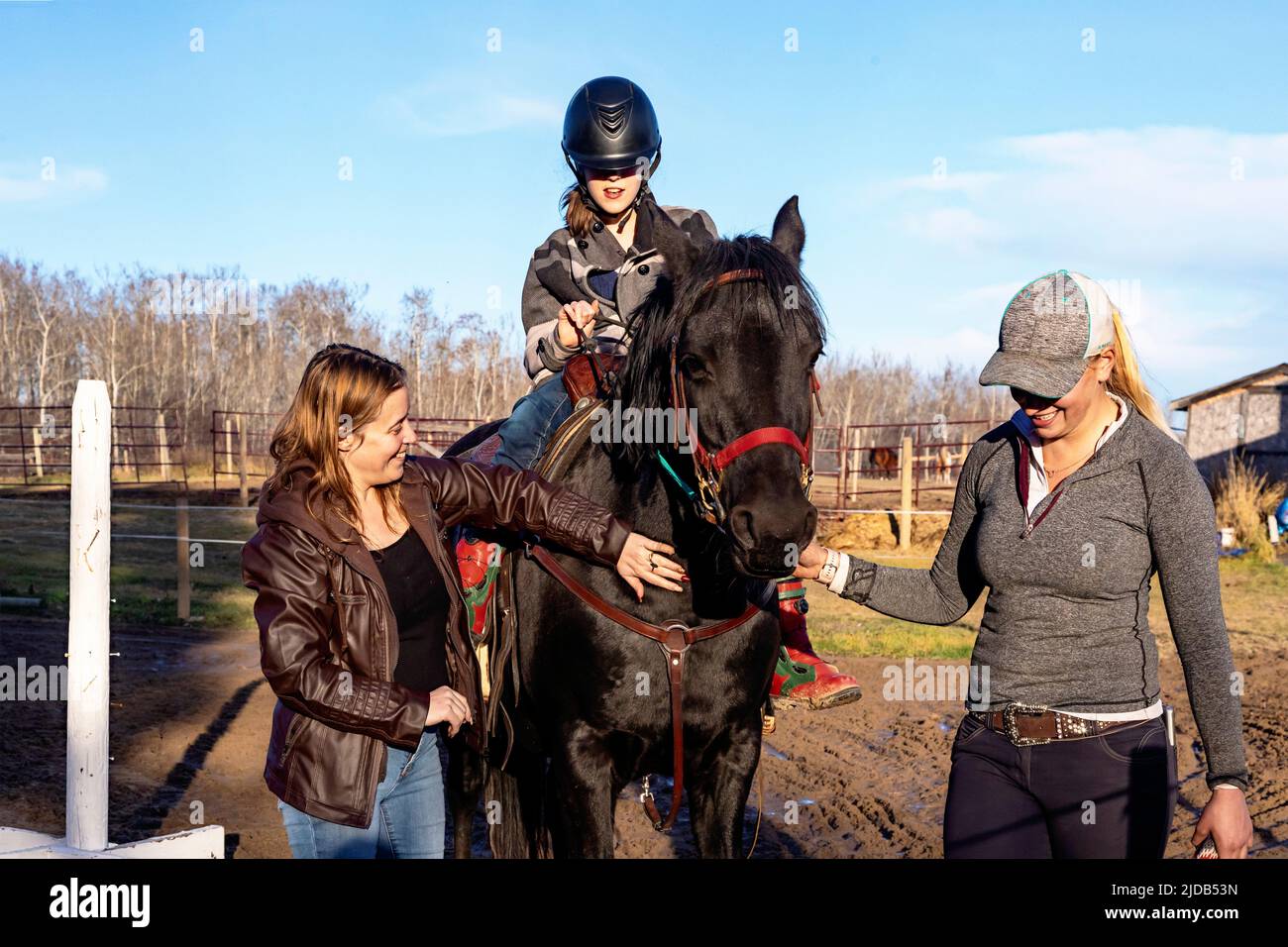 A young girl with Cerebral Palsy, her Mom and her trainer working with a horse during a Hippotherapy session; Westlock, Alberta, Canada Stock Photo