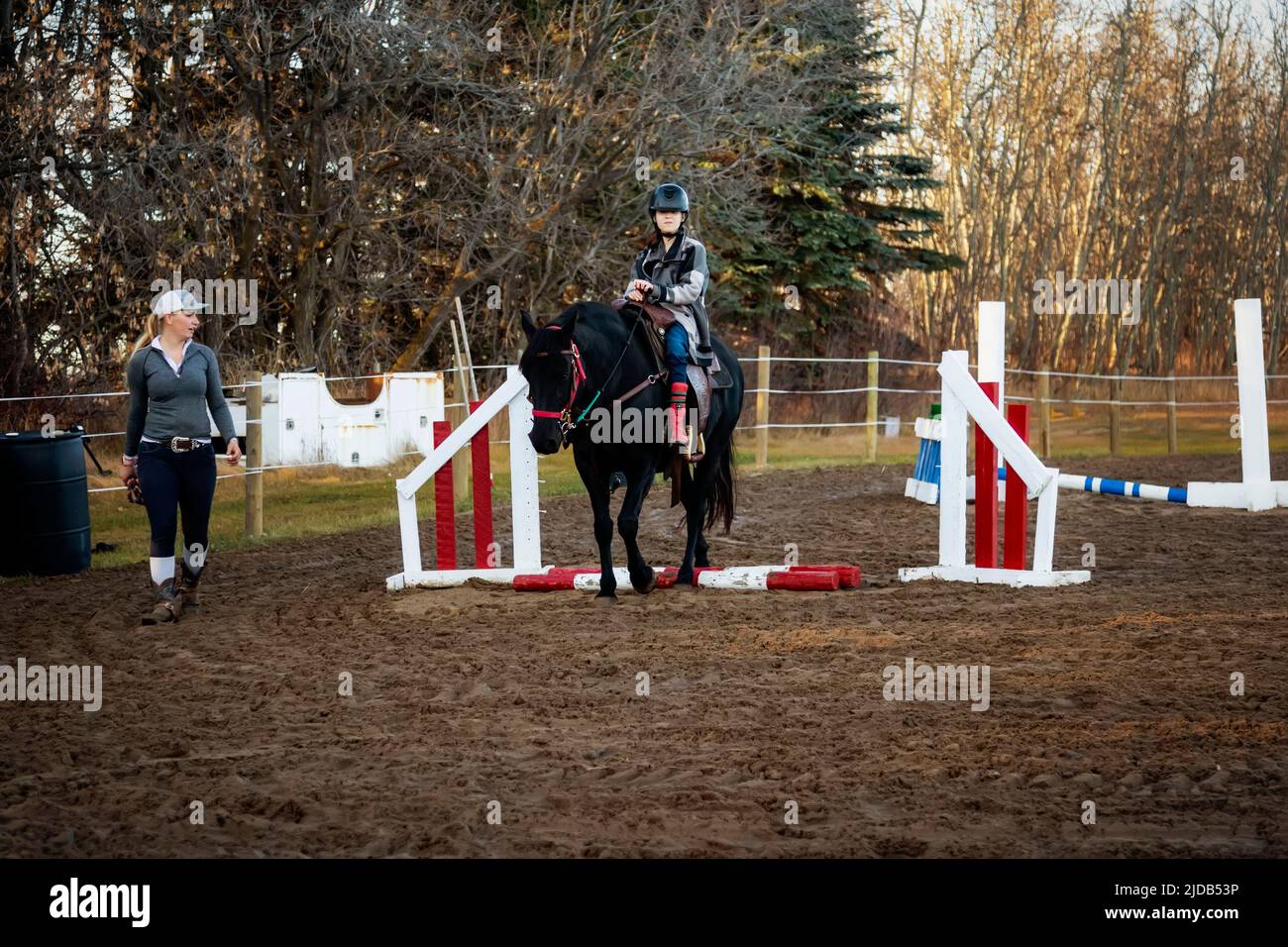 A trainer working with a young girl with Cerebral Palsy during a Hippotherapy session; Westlock, Alberta, Canada Stock Photo