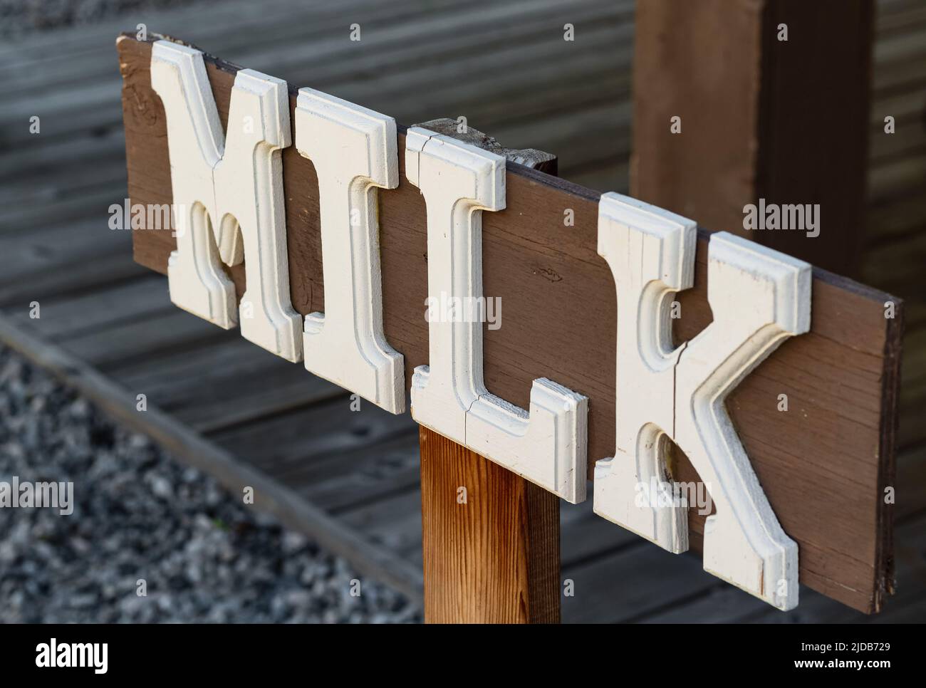 Wooden board with word milk. Signboard with directions to buy milk. White Milk writing with letters on dark background. Stock Photo