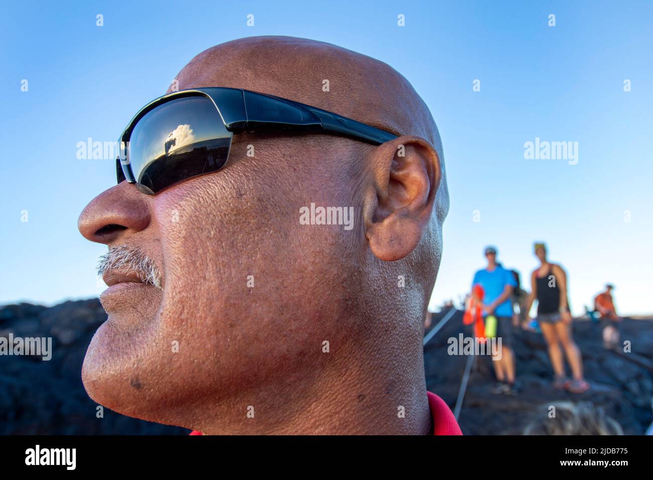 The lave ocean entry on the Big Island of Hawaii is reflected in the sunglasses a local tour guide in January 2017. Jim Lavrakas/Far North Photo Stock Photo