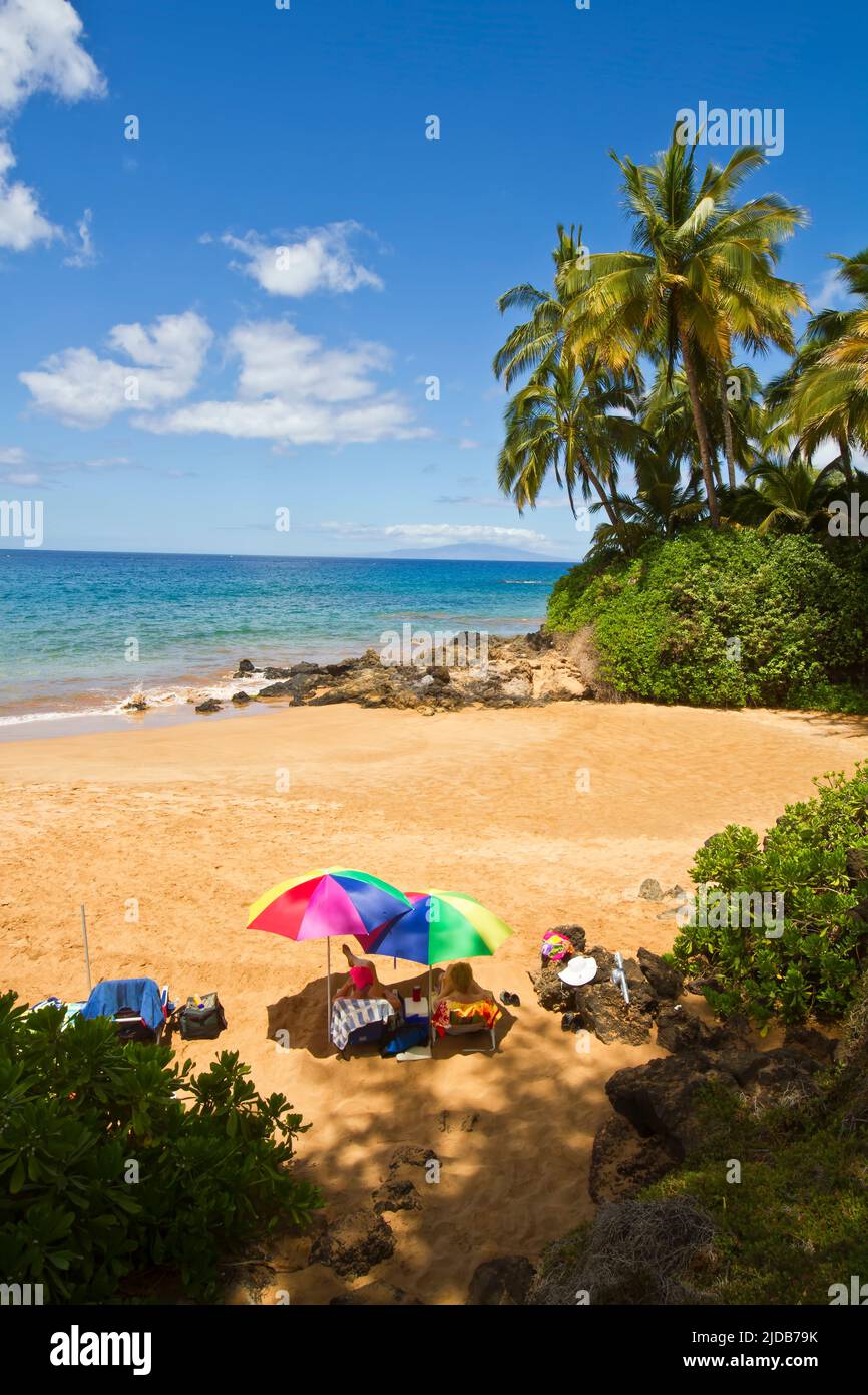 Couple relaxing at North end of Po'olenalena Beach under umbrellas,  Makena, Maui, Hawaii MNR Stock Photo