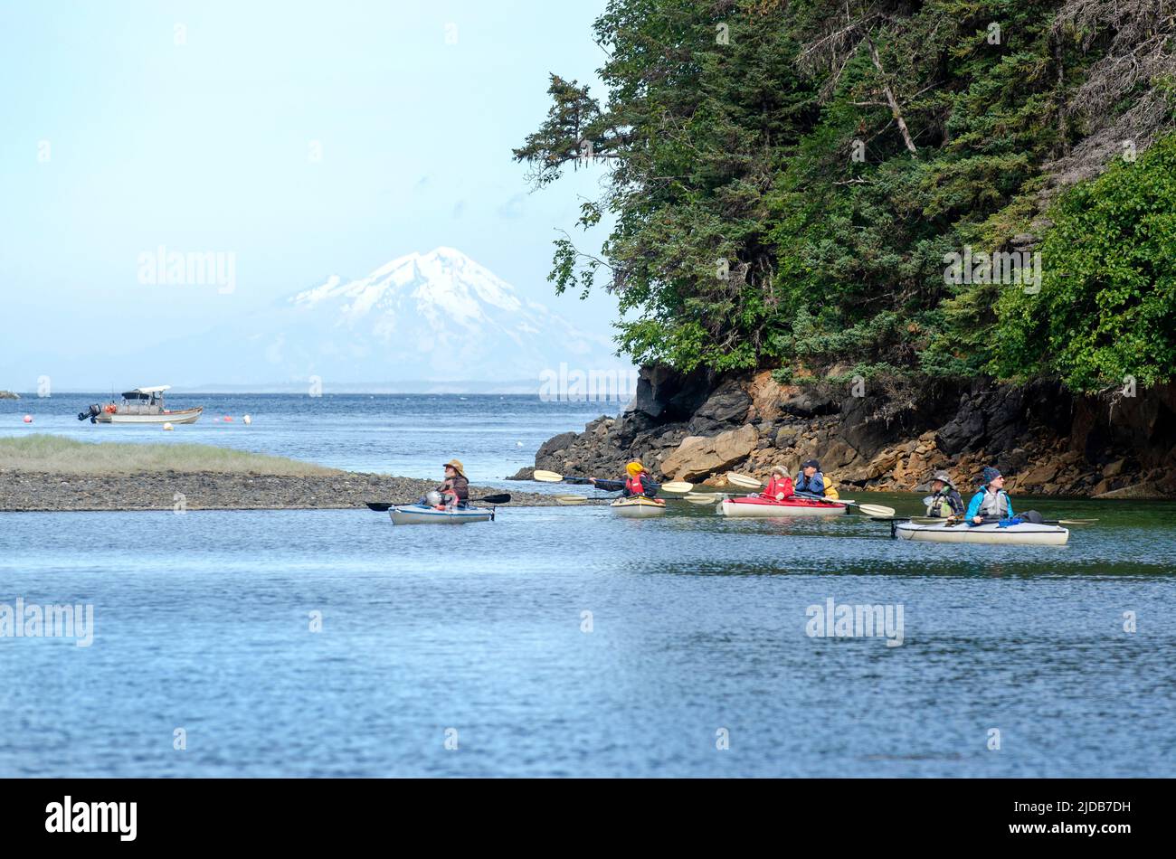 Kayakers paddle through a lagoon in Little Tutka Bay, in Kachemak Bay,  with Mount Redoubt volcano in the background. Jim Lavrakas/Far North Photo Stock Photo