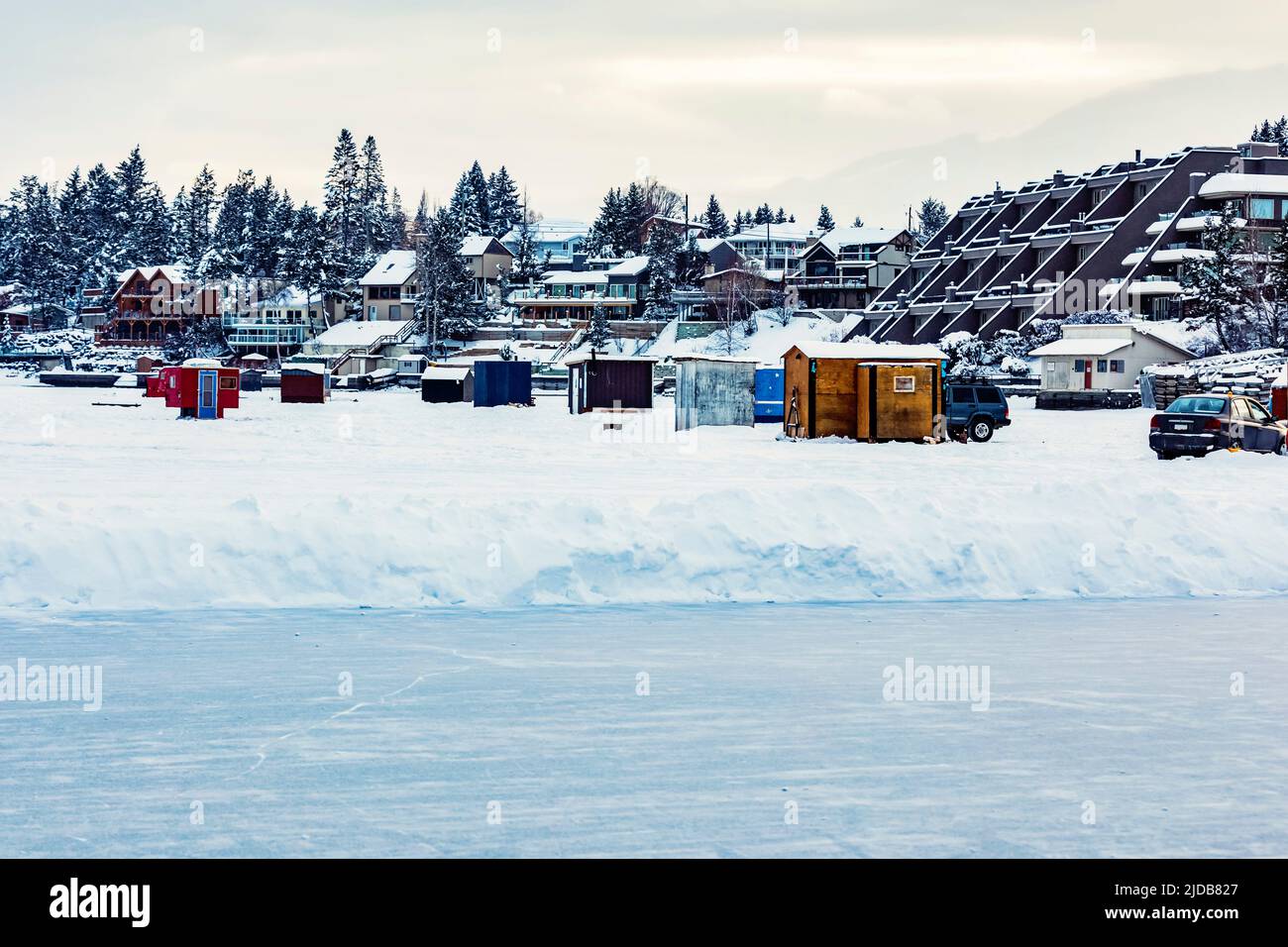 View of skating rink and ice fishing shacks and trailers on the shoreline of Windermere Lake: Invermere, BC, Canada Stock Photo