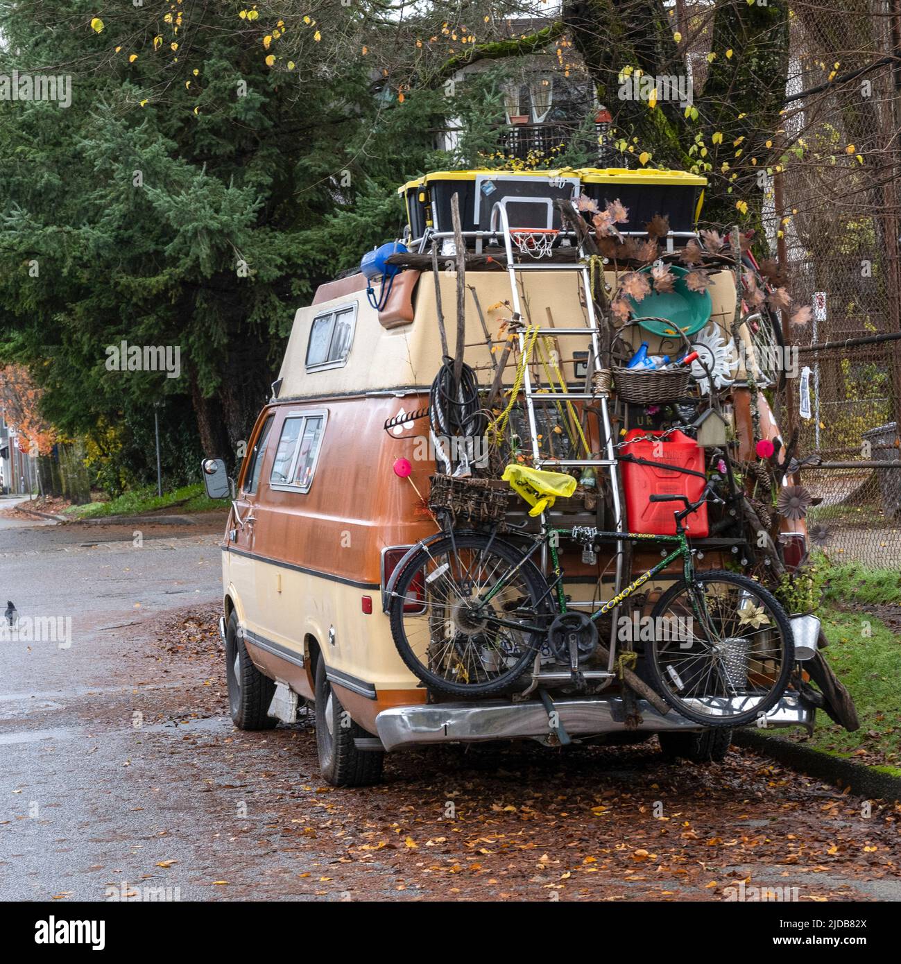 A camper van loaded with household goods including a bicycle parked and on a residential street; Vancouver, British Columbia, Canada Stock Photo
