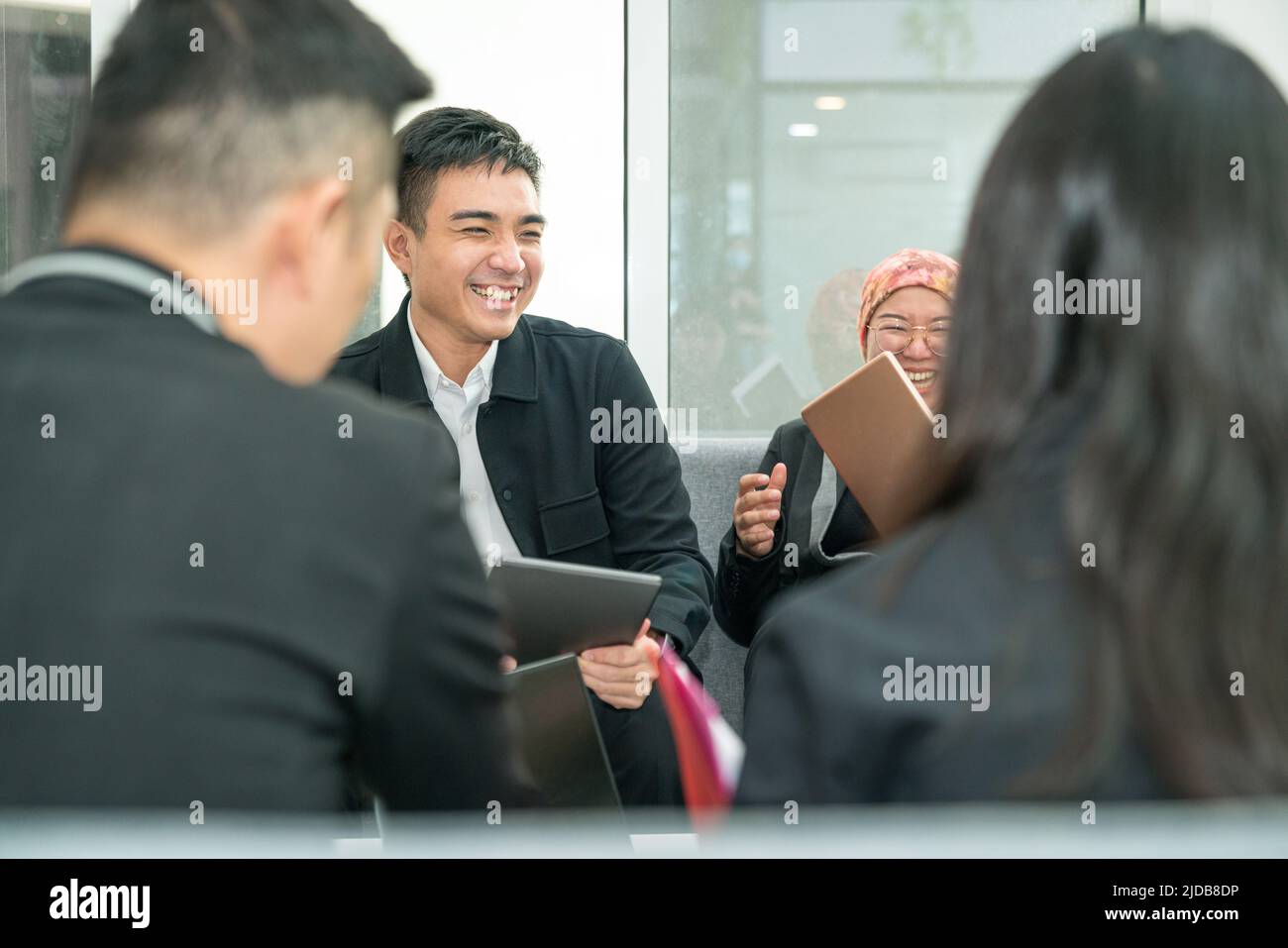 Office colleagues laughing in the midst of a meeting. Having fun working together in a project. Stock Photo