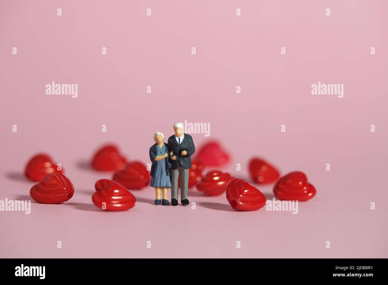 Miniature people toys conceptual photography. Man and women elderly standing in the center of heart shape. Couple in love concept. Image photo Stock Photo