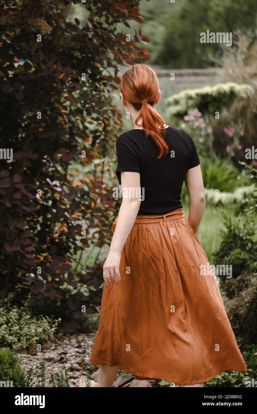 Happy ginger hair woman walking barefoot in the park or garden. Freedom and healthy way of life. Female in her 40s having rest outdoors. People in Stock Photo