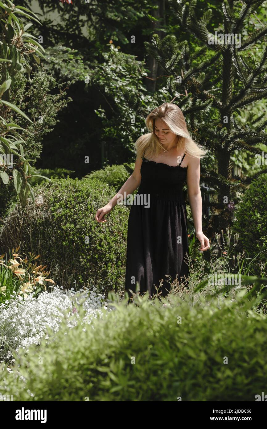 Happy blond woman walking barefoot in the park or garden. Freedom and healthy way of life. Female in her 30s having rest outdoors. People in motion Stock Photo