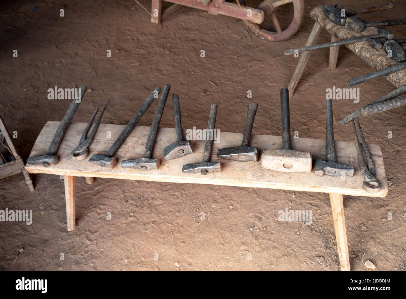 A row of hand tools on a colonial american rustic wooden bench in a Pennsylvania historical workshop. Dirt floor interior with no people and copy spac Stock Photo