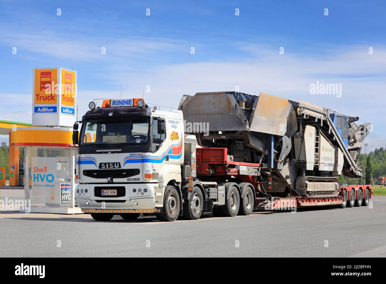 White Sisu 18E630 truck of O.Rinne Oy carrying Kleemann crusher on low loader trailer at Shell truck fueling station. Forssa, Finland. June 10, 2022 Stock Photo