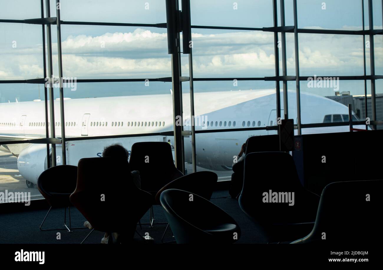 Airliner airplane behind the window seen from the waiting area, departures lounge at the airport terminal. Stock Photo