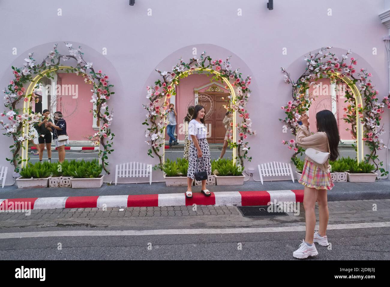 Tourists take photos in front of the mirrored windows of Aung Ku Cafe in Soi Rommanee / Thalang Rd in the Old Town area of Phuket Town, Thailand Stock Photo