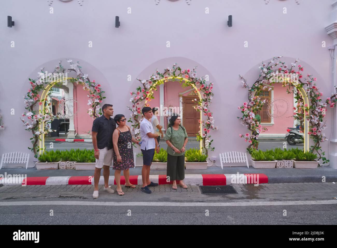 Indian tourists pose in front of the mirrored windows of Aung Ku Cafe in Soi Rommanee / Thalang Rd in the Old Town area of Phuket Town, Thailand Stock Photo
