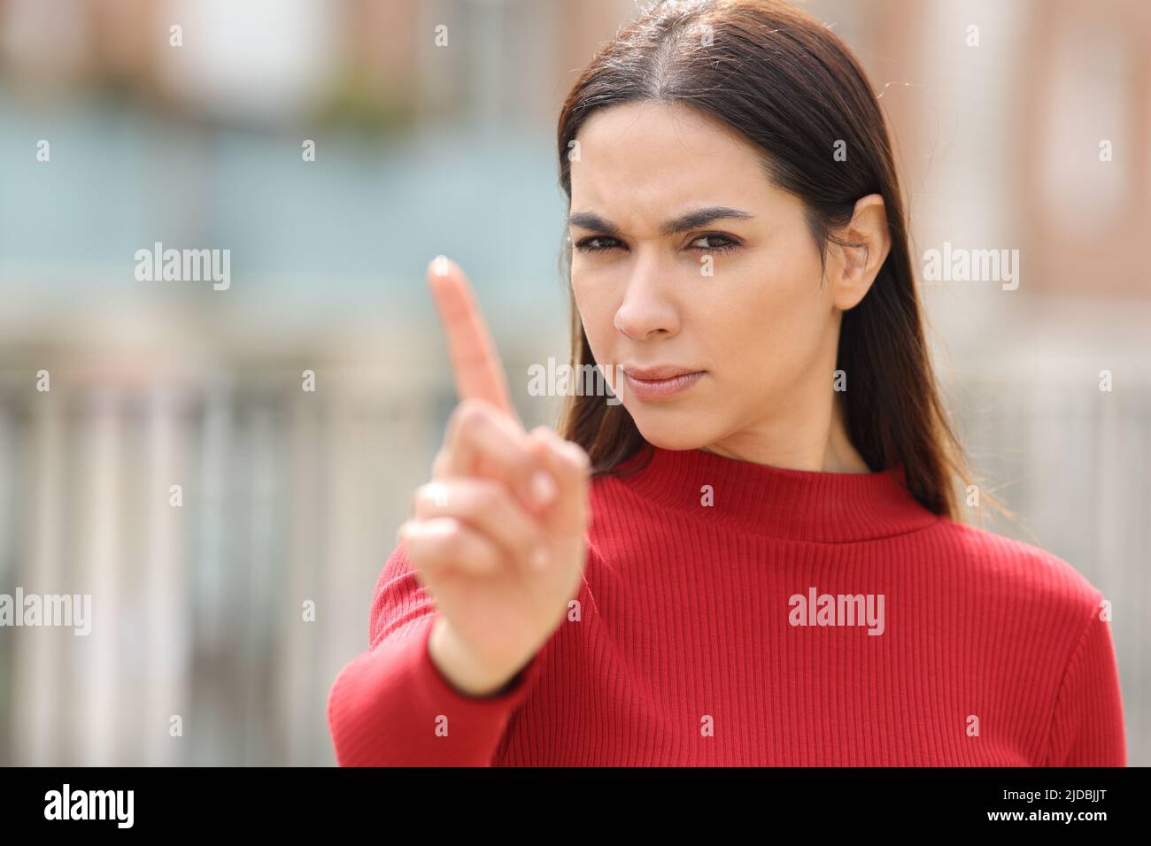 Angry woman in red gesturing no with her hand in the street Stock Photo