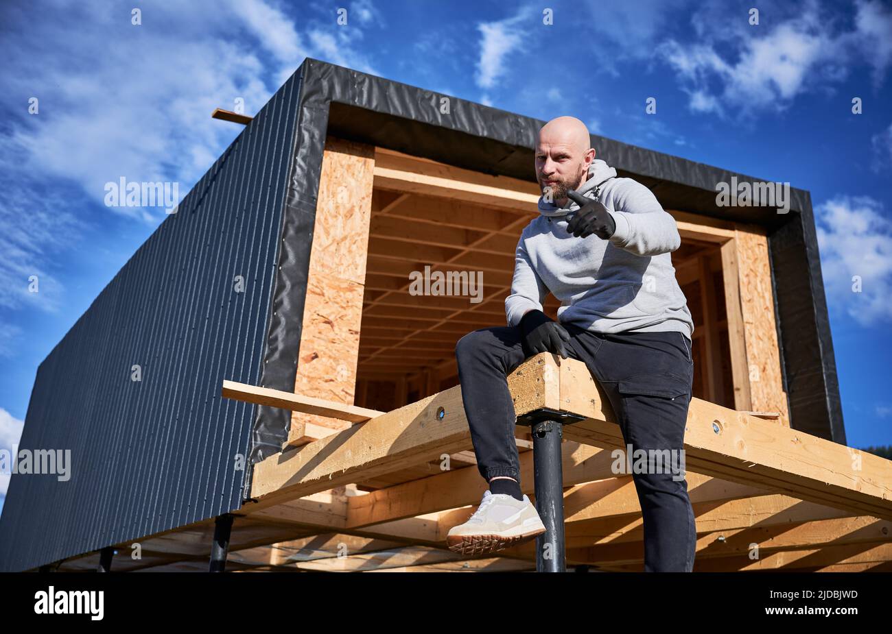Male developer building wooden frame house on pile foundation. Portrait