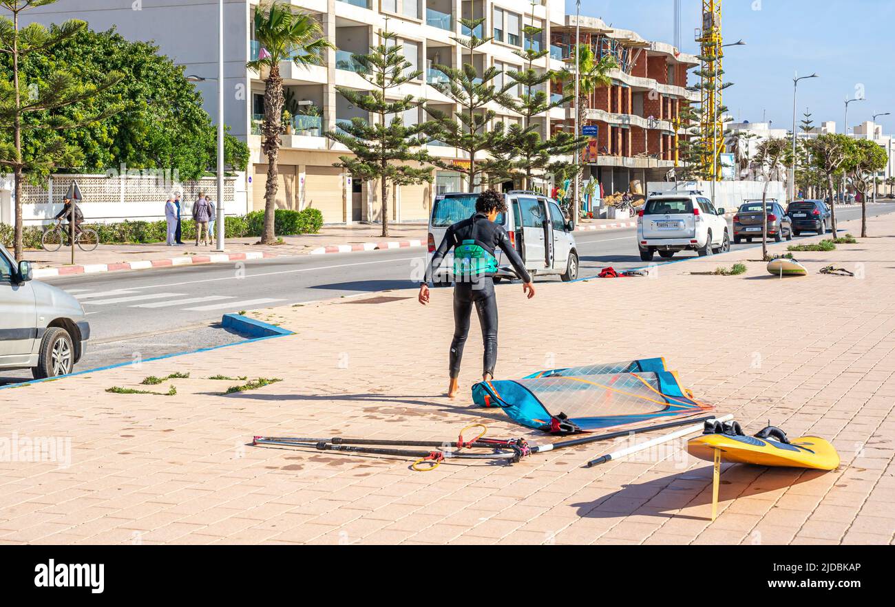 A young man with two boards after surfing in the street of the port city of Essaouira, Morocco Stock Photo