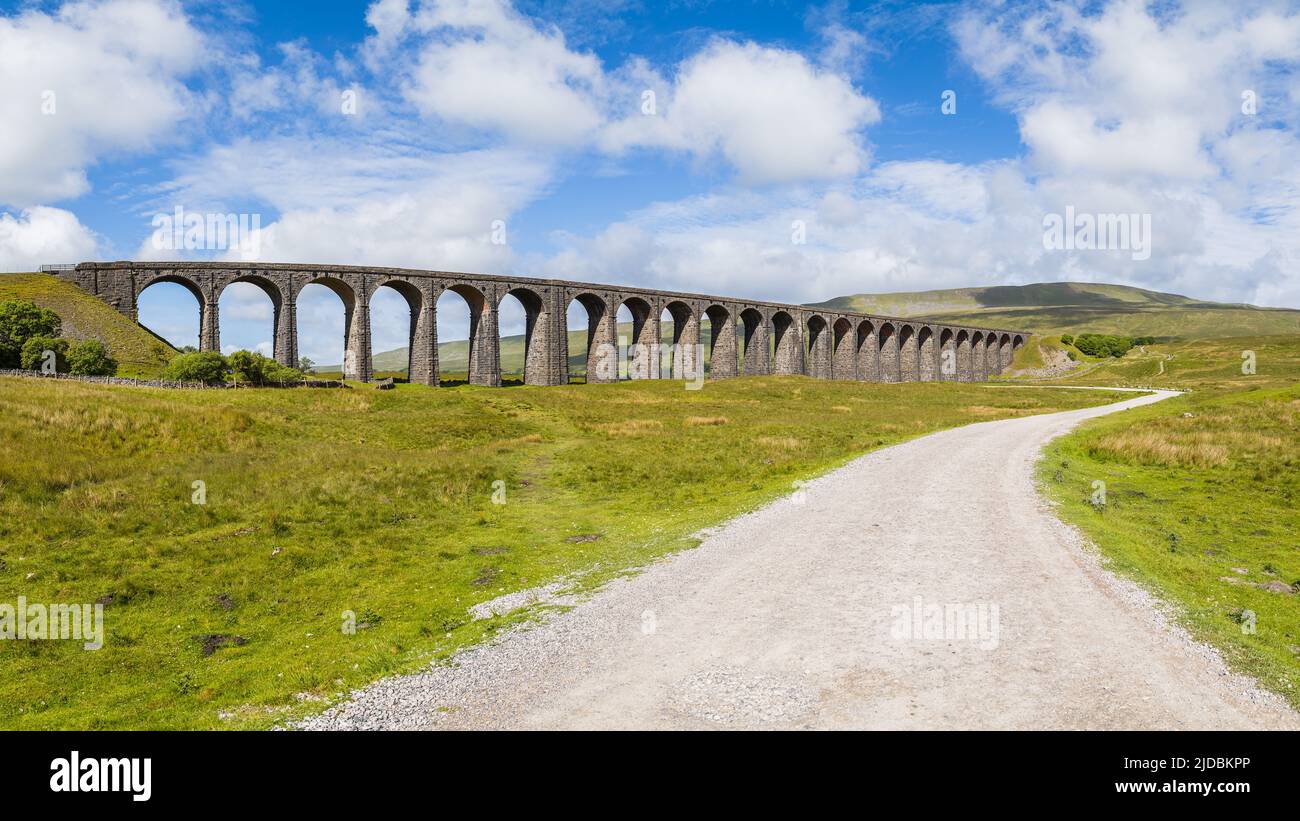 Multi image panorama of a pathway leading to the Ribblehead Viaduct in North Yorkshire seen under a bright blue sky. Stock Photo