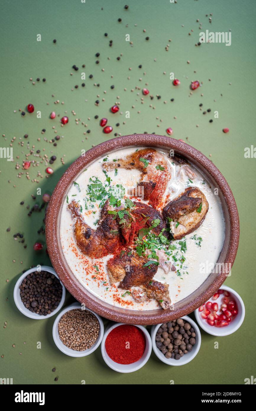 top view of georgian chkmeruli chiken meat in cream sauce in clay bowl and spice Stock Photo
