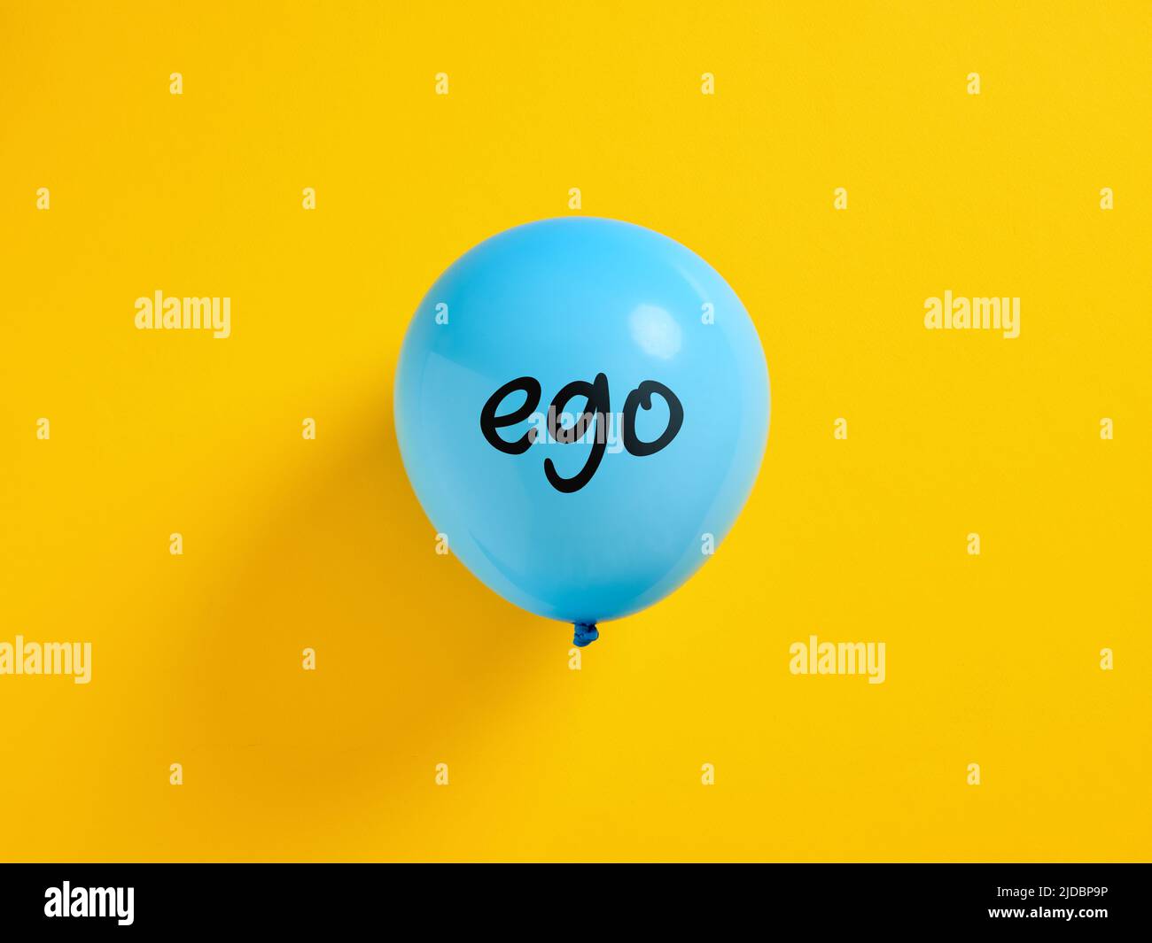 Inflated blue balloon with the word ego and a pin. Selfishness or inflated extreme ego concept. Stock Photo
