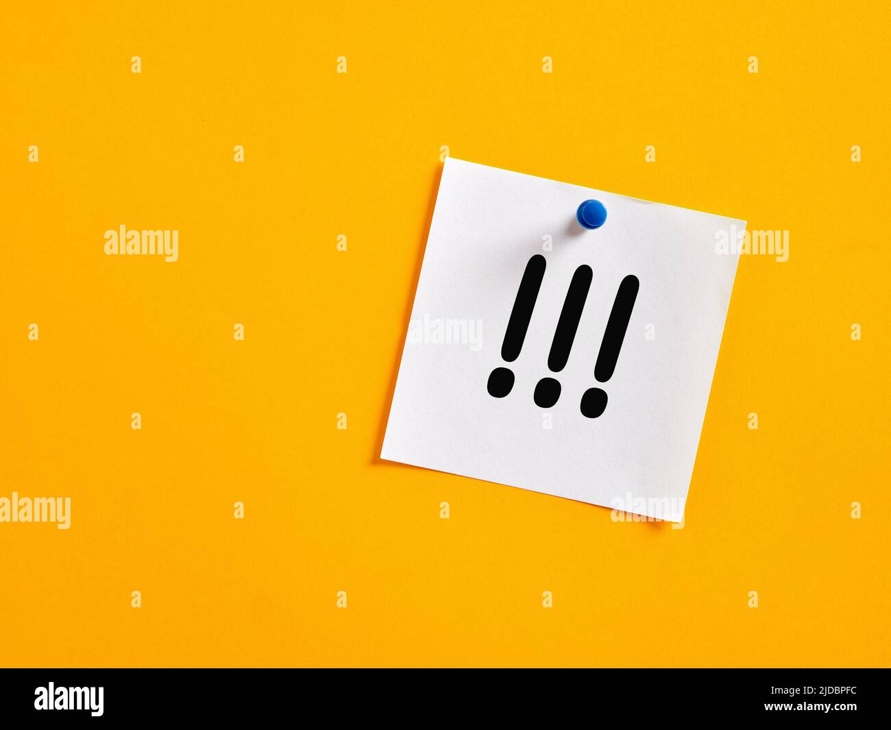 Three handwritten exclamation marks on a note paper pinned on a yellow