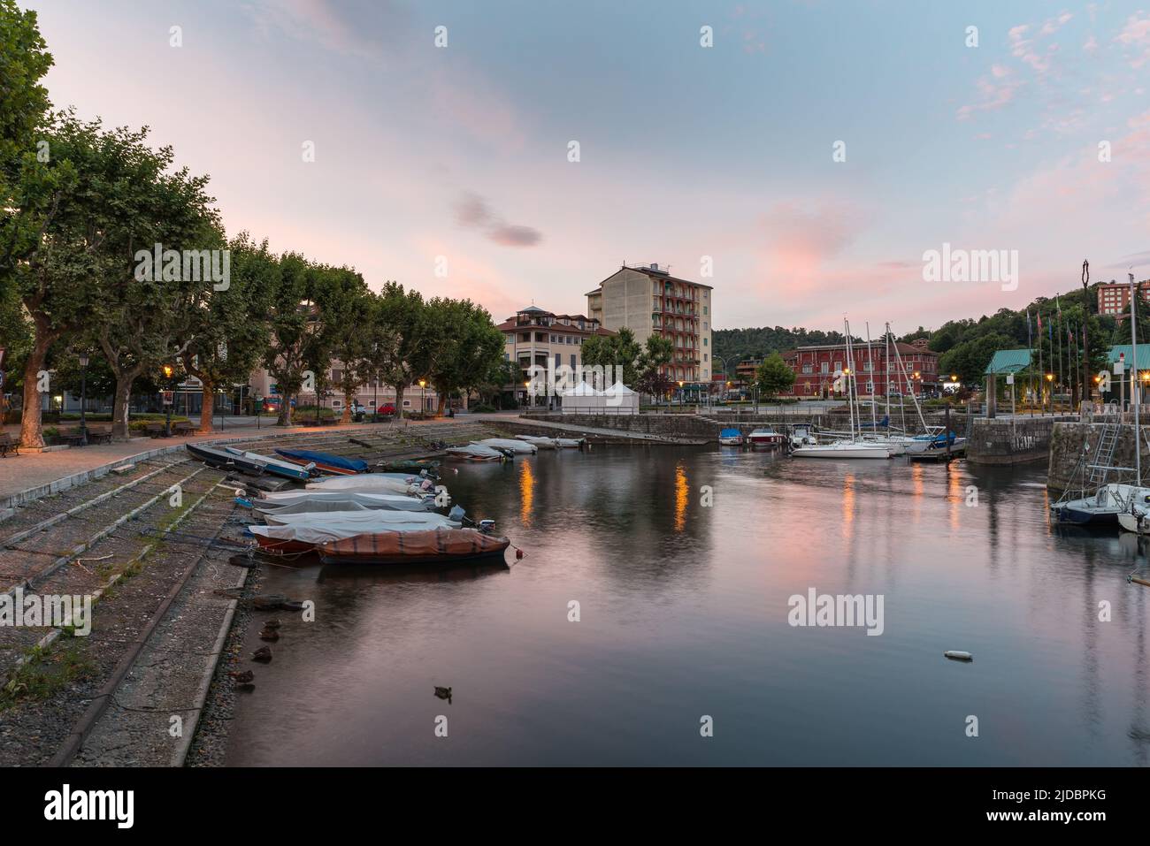 Small harbor on the lake. Lake Maggiore at sunrise in Laveno town, Italy, with the lakeside promenade on the left Stock Photo