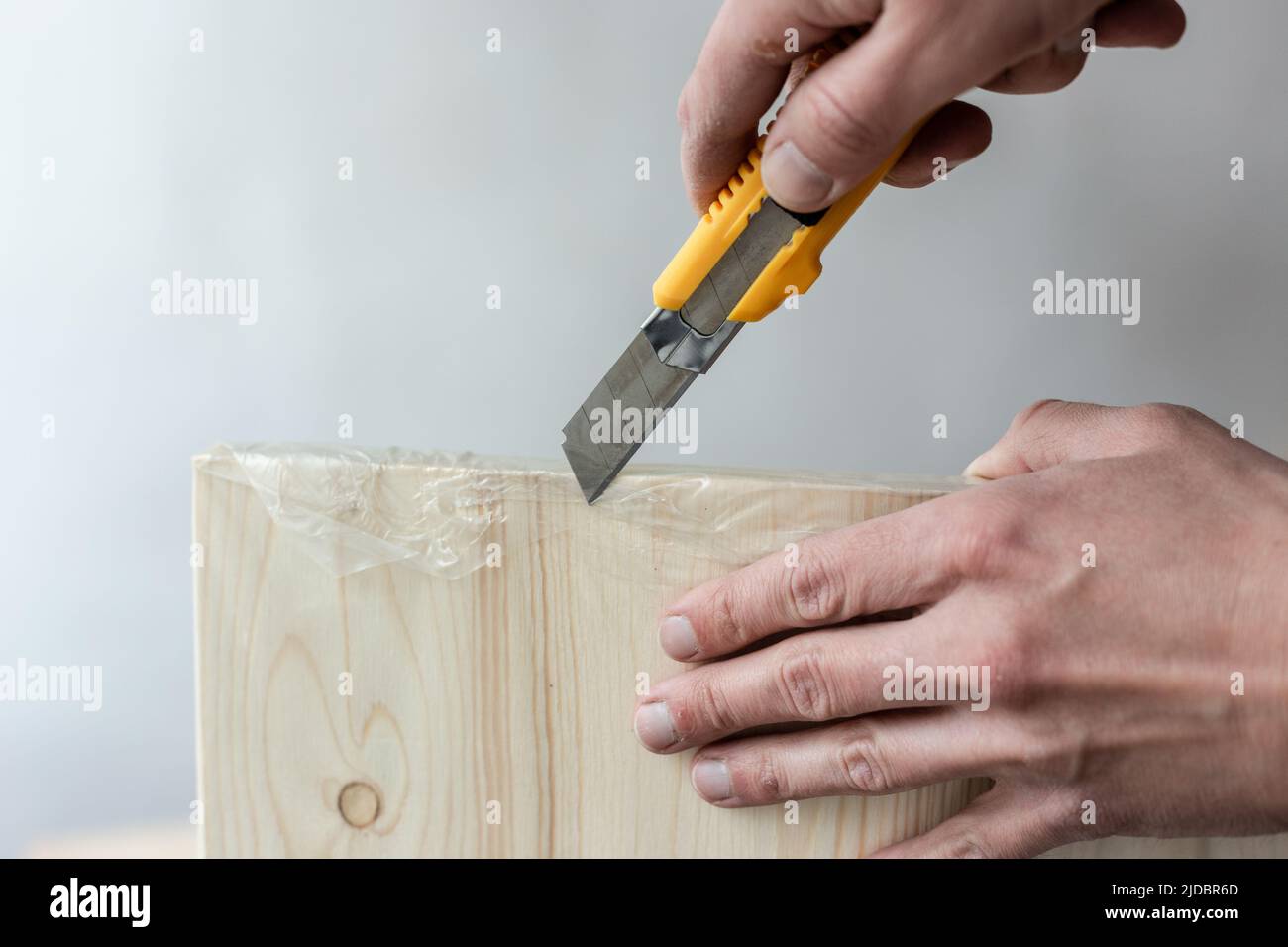 Unpacking a furniture board with a knife. Unpacking a wooden board ...