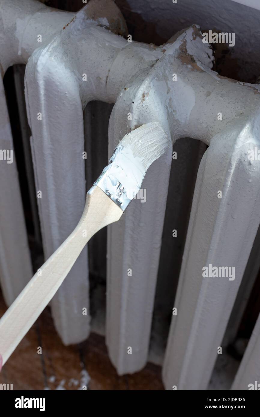 Painting radiators with a special brush. Battery painting Stock Photo