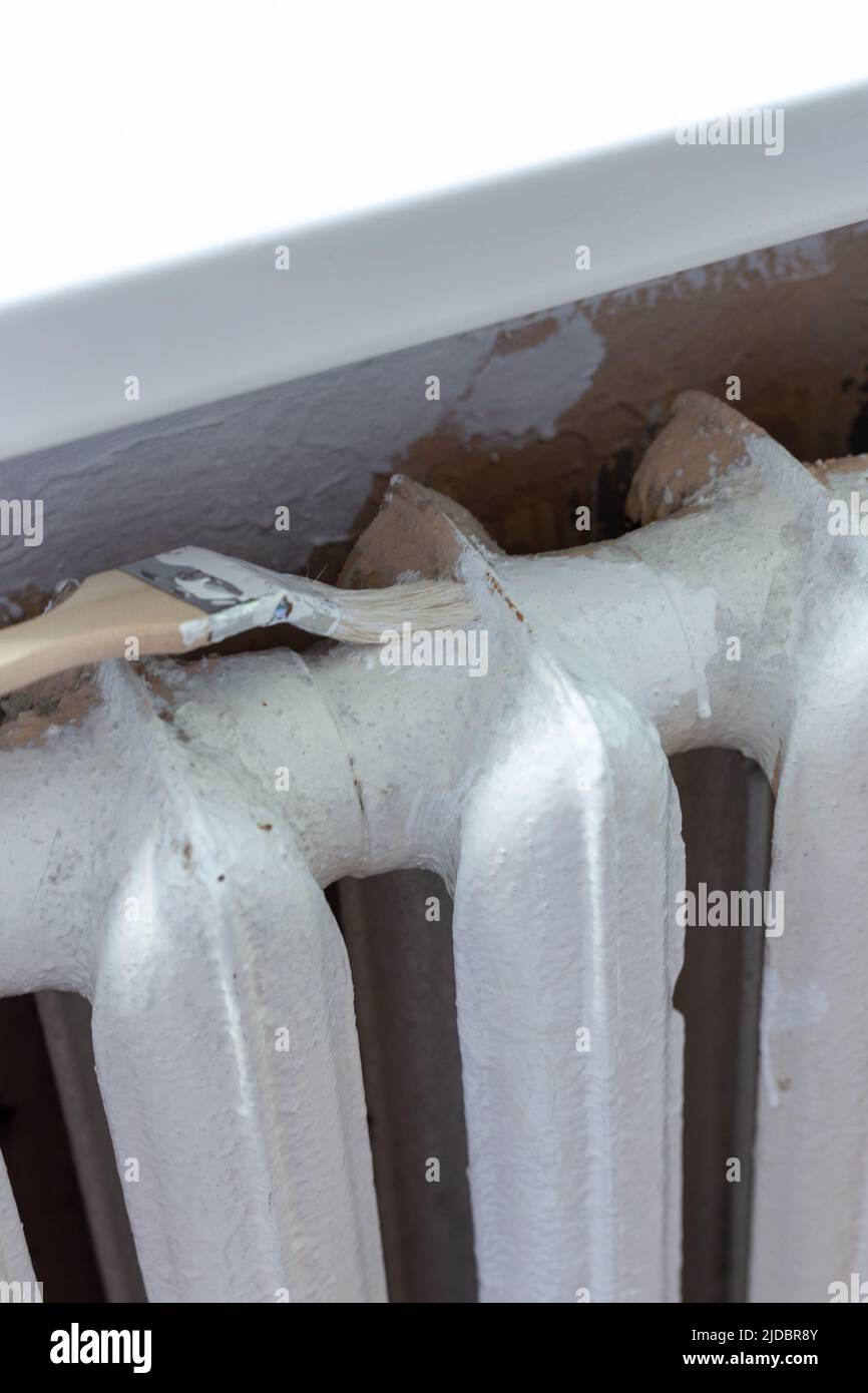 Painting radiators with a special brush. Battery painting Stock Photo