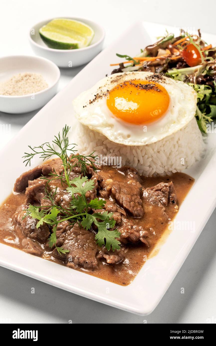 Traditional cambodian Lok Lak stir fried beef with rice meal on white background Stock Photo