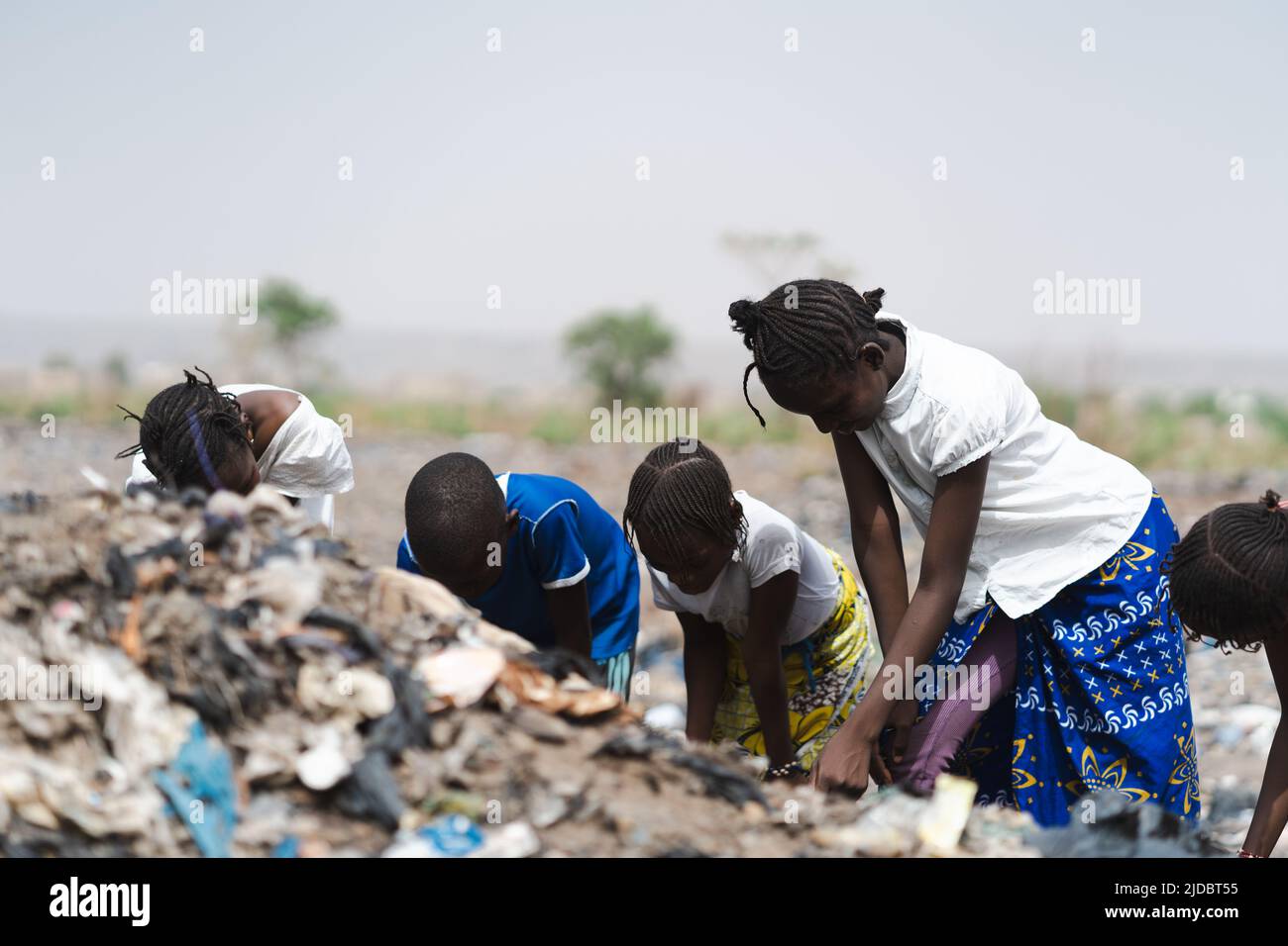 Four West African homeless children digging in a landfill looking after recyclable items to sell; poverty concept Stock Photo