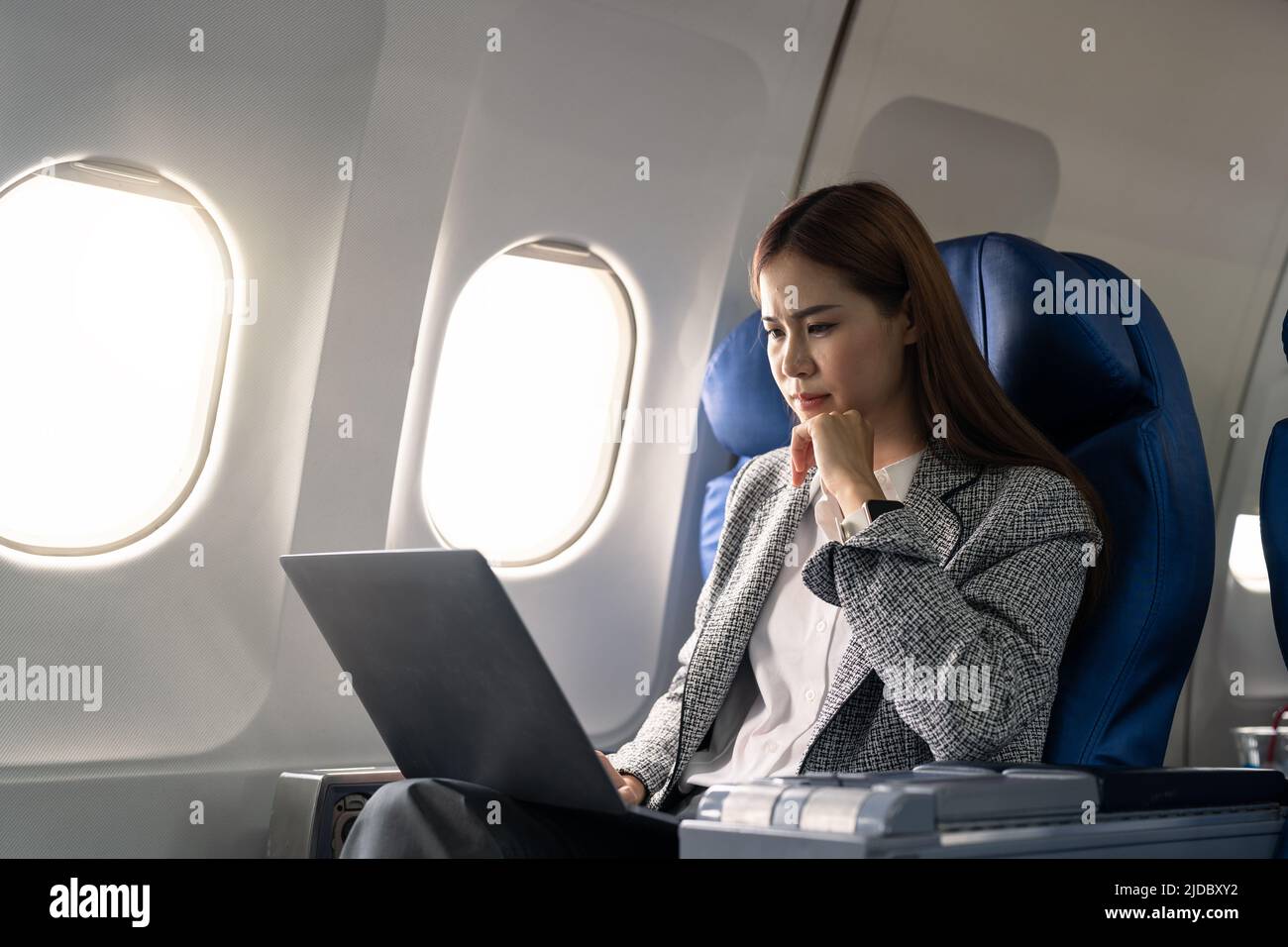 Asian young woman using laptop sitting near windows at first class on airplane during flight, Traveling and Business concept Stock Photo