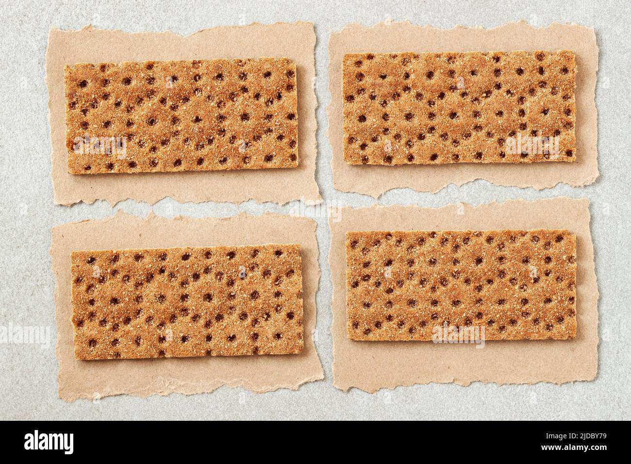 Set of rye crunchy crispbread on craft paper pieces with with torn edges. Dietetic Crackers. Abstract Food background Stock Photo