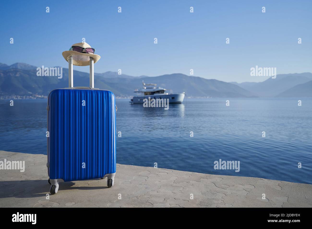Blue suitcase by the sea against yacht, travel concep. Stock Photo