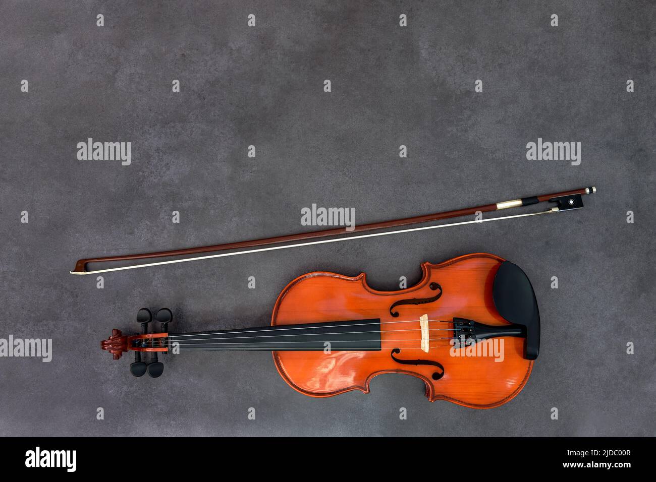 Violin and bow on gray wood background. Flat lay, top view, copy space. Concept of classical