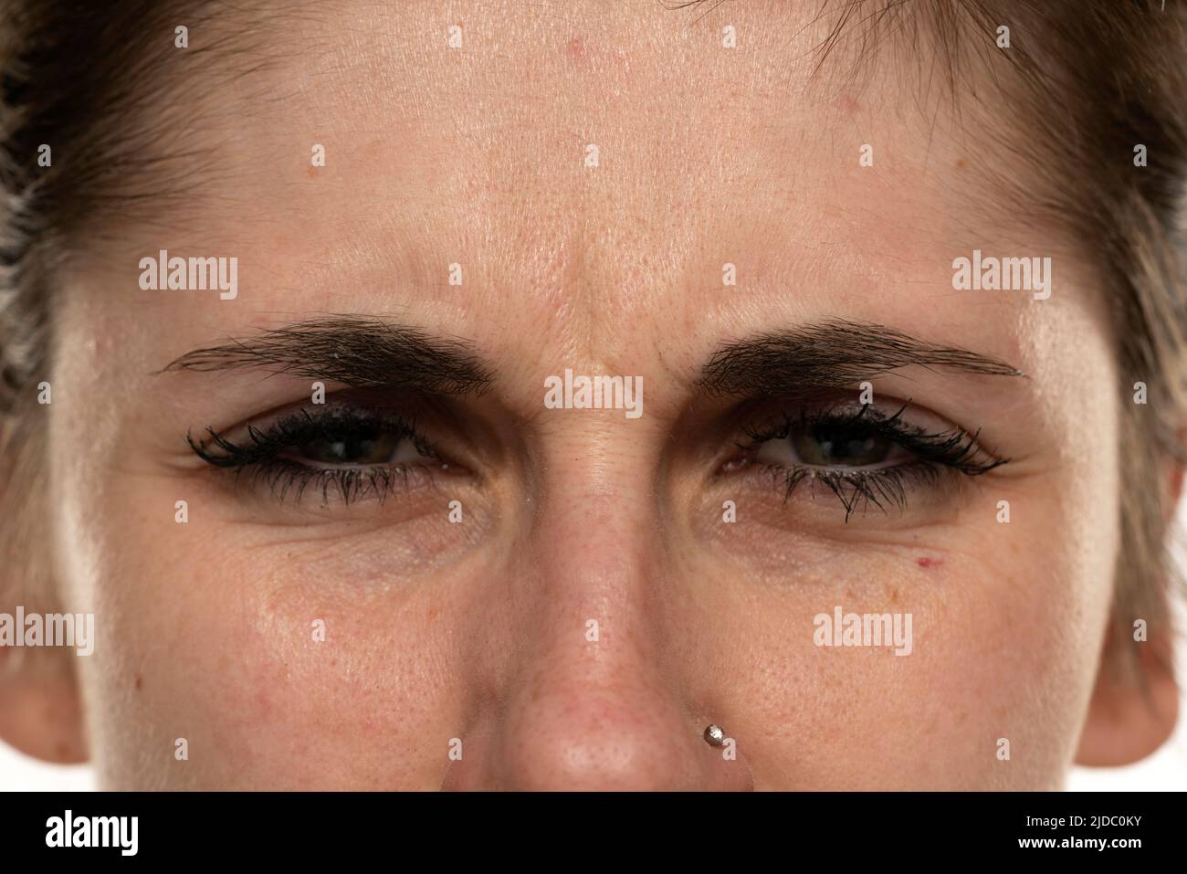 Angry face of a young woman with facial wrinkles closeup. Stock Photo