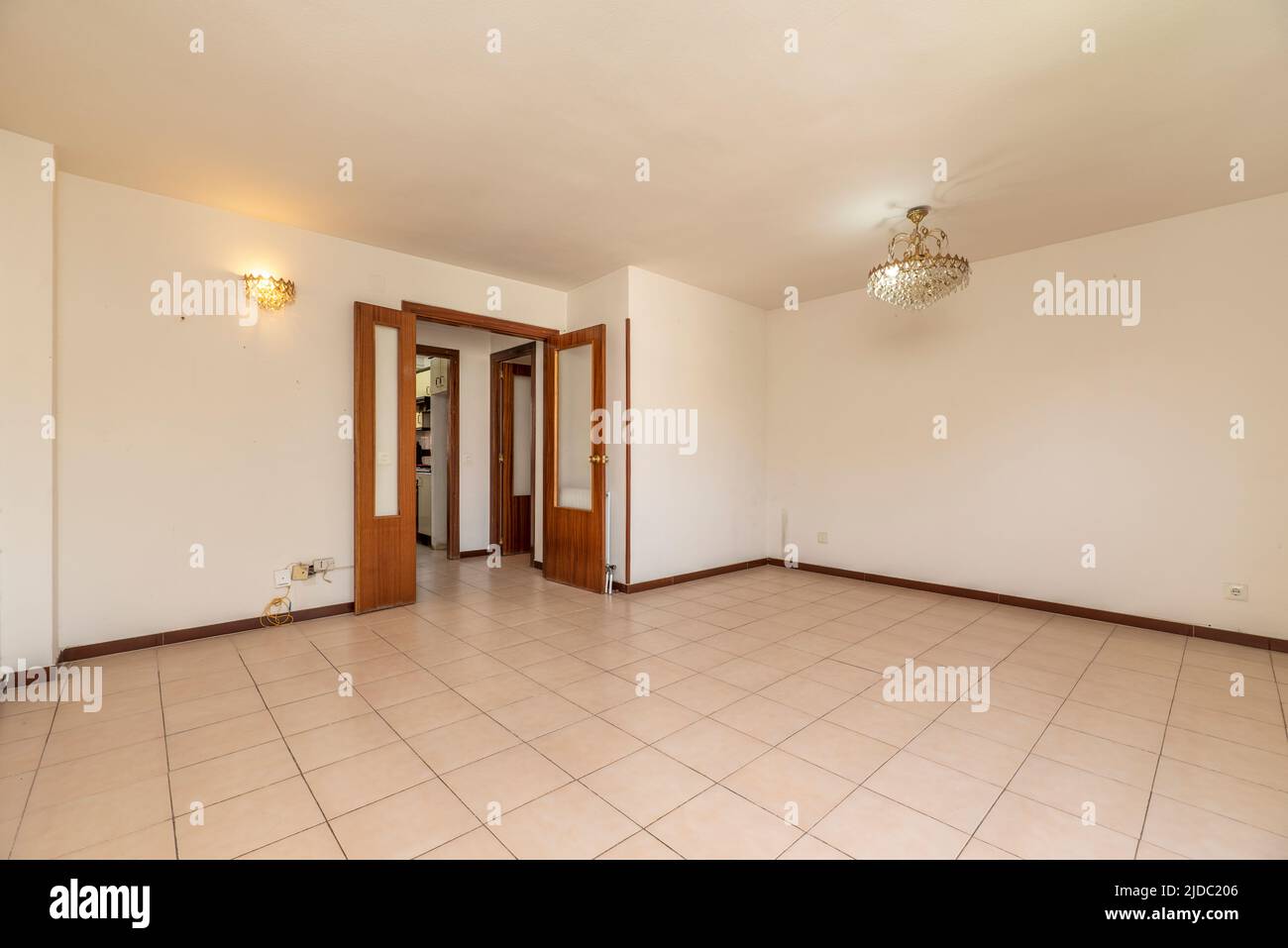 An empty living room with white painted walls, cream stoneware floor, wooden carpentry and glass lamps Stock Photo
