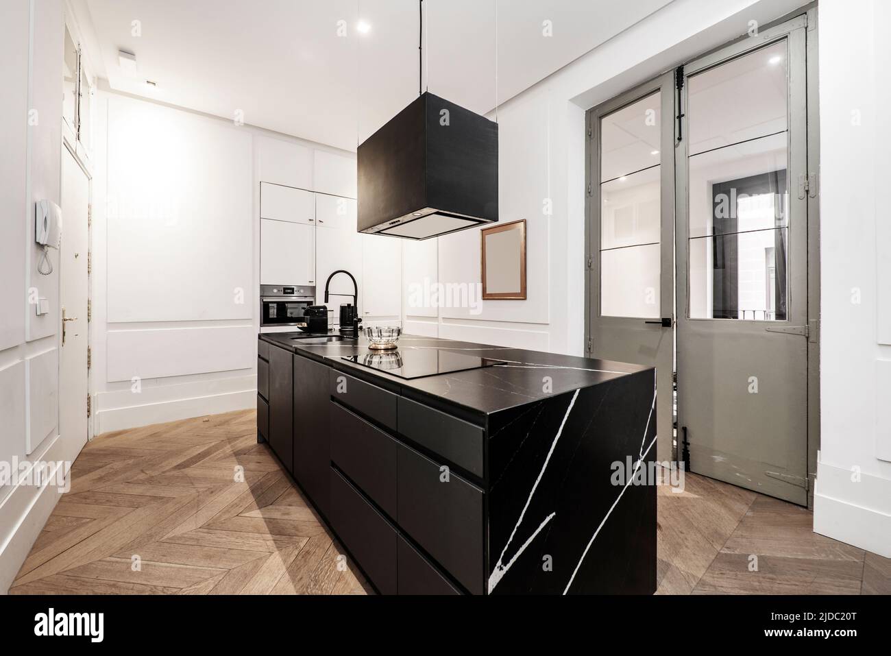 Modern kitchen with central island of wood and black marble, matching extractor hood and oak wood floor Stock Photo