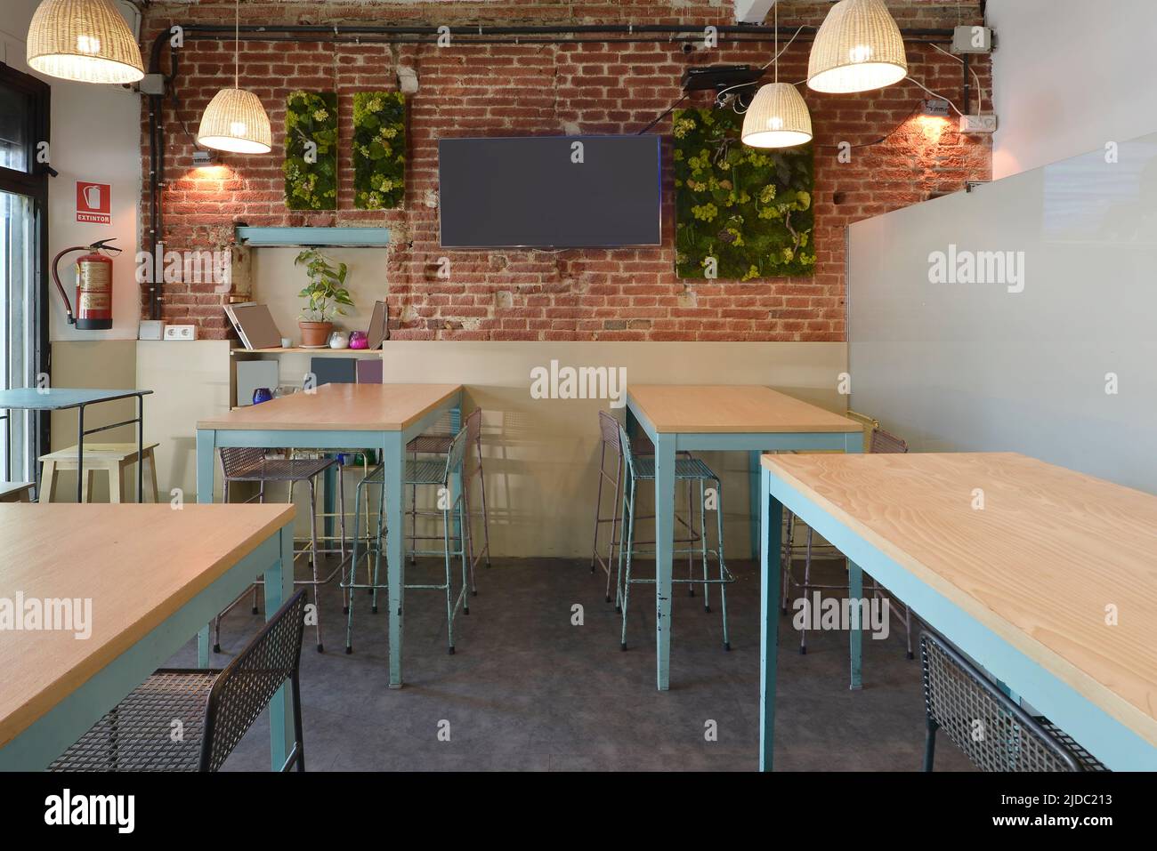 Tall metal and wood tables and chairs in dining room with exposed brick
